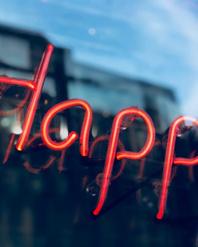 A neon sign with the word happy to demonstrate the topic of the blog.