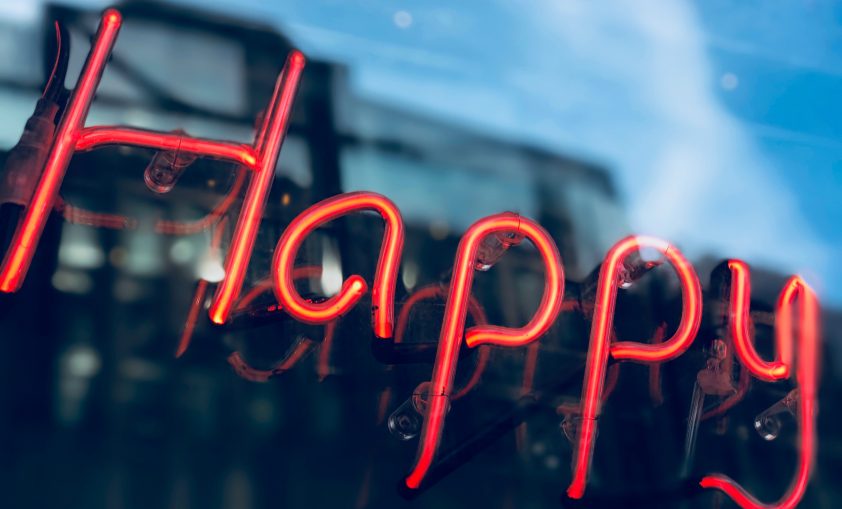 A neon sign with the word happy to demonstrate the topic of the blog.