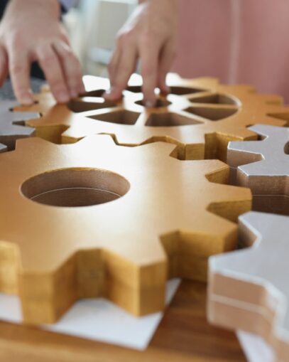Hands on top of wooden machine cogs