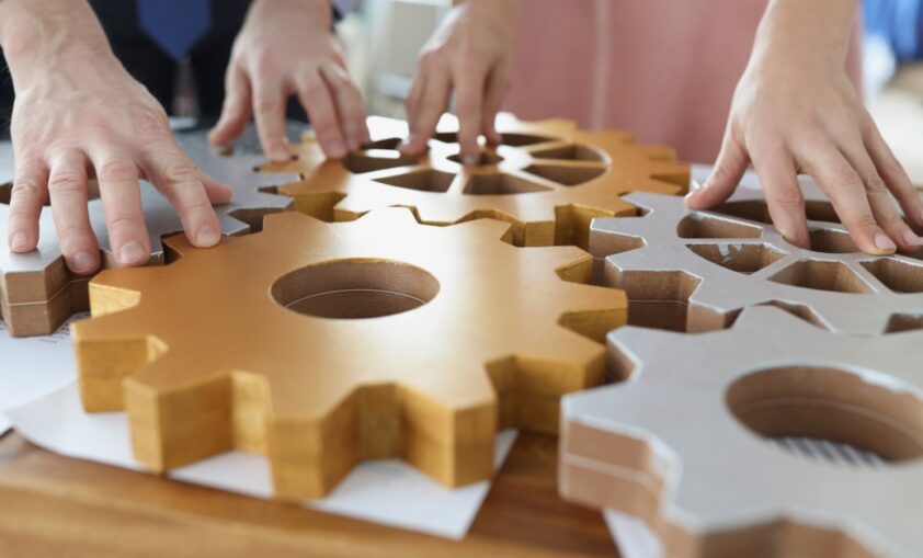 Hands on top of wooden machine cogs