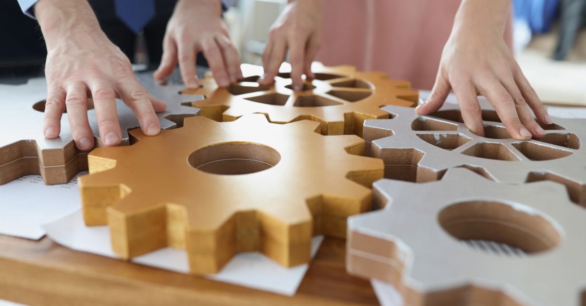Hands on top of wooden machine cogs